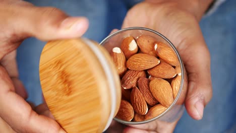 Top-view-of-hand-pick-almond-nuts-from-a-bowl-,
