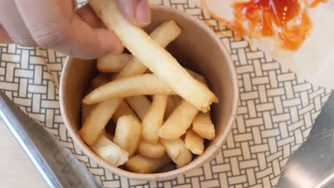 Hand-pick-french-fries-on-table-,