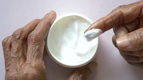 Senior-woman-applying-beauty-cream-onto-skin