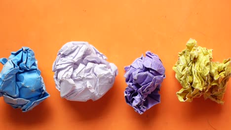 Top-view-of-crumpled-paper-balls-on-orange-background