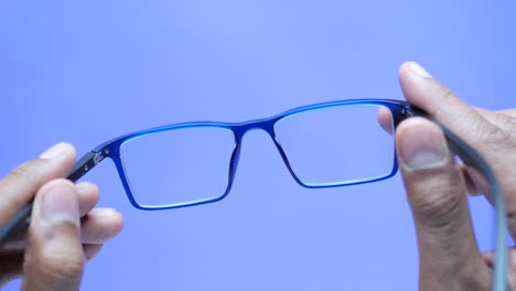 Close-up-of-man-hand-holding-blue--eyeglass,