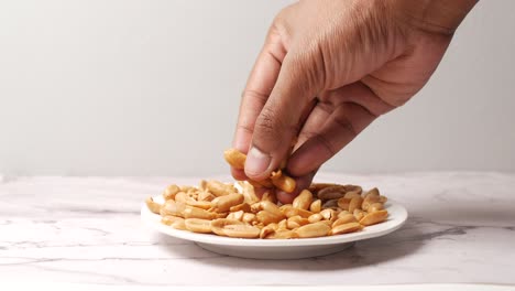 Side-view-of-hand-pick-peanuts-from-a-plate-,