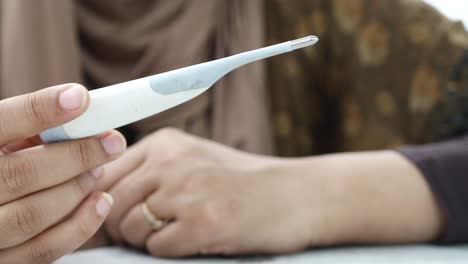 Close-up-of-women-holding-a-digital-thermometer