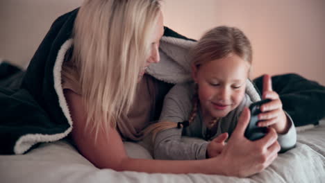 Mom,-daughter-and-smartphone-in-bedroom