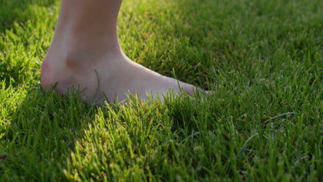 Child's-feet-walking-on-green-grass,-close-up-of-walking-foot