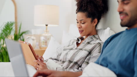 Couple,-tablet-and-laptop-with-talking-in-bed