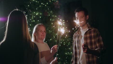 A-happy-family-celebrates-the-new-year-at-the-Christmas-tree,-holding-burning-sparklers