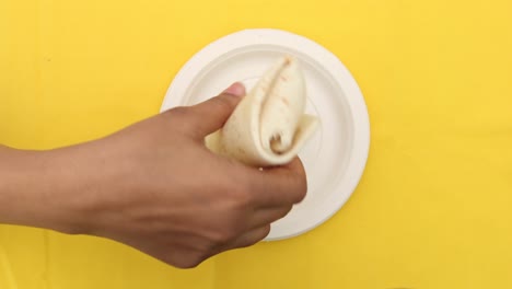 Women-hand-pick-chicken-wrap-from-a-plate-,