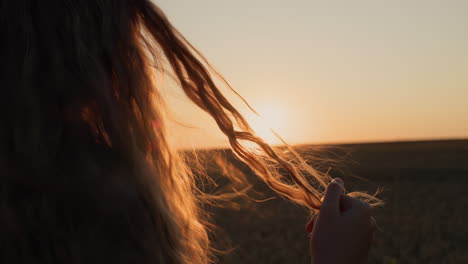 Cute-woman-looks-at-her-hair-in-the-sun,-holds-a-lock-of-hair-in-her-hand