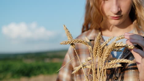 Close-up-Portrait-of-a-teenage-girl-with-spikelets-of-wheat-in-her-hand.-Set-against-a-backdrop-of-picturesque-countryside
