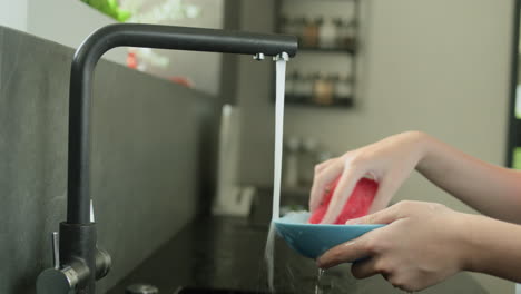 Children's-hands-washing-a-dirty-plate-under-running-water-from-a-kitchen-faucet