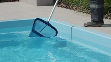 A-worker-removes-debris-from-a-pool-with-a-net.-Close-up-shot