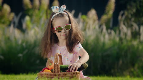 Ein-Süßes-Kind-Sitzt-Auf-Dem-Rasen-Neben-Einem-Gemüsekorb.-Picknick-Konzept