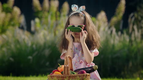 A-cute-child-is-sitting-on-the-lawn-near-a-basket-of-vegetables.-Picnic-concept