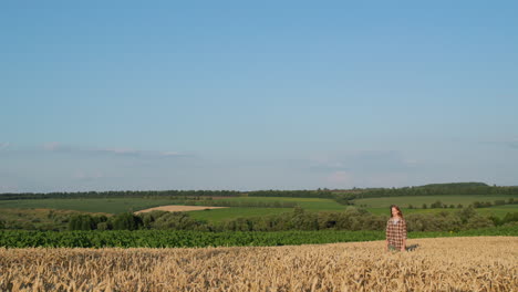 A-girl-with-long-hair-walks-along-a-field-of-wheat-in-a-picturesque-countryside