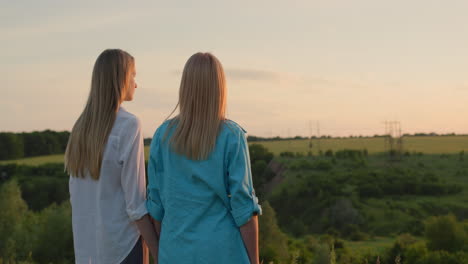 A-woman-with-her-teenage-daughter-admire-the-sunset-in-a-picturesque-valley