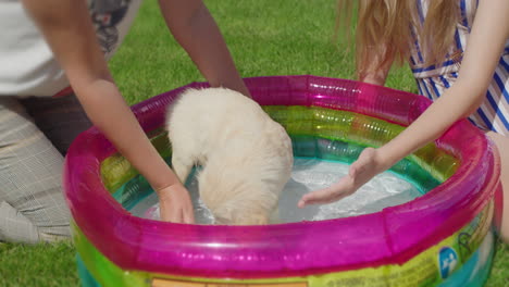 Mom-and-daughter-bathe-a-fluffy-puppy-in-a-small-inflatable-pool