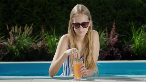Portrait-of-a-teenage-girl-in-the-pool-with-a-glass-of-soft-drink