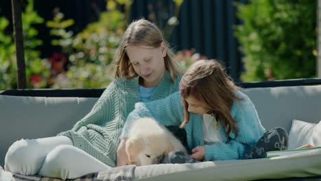 Two-girls-playing-with-a-puppy,-sitting-on-a-swing-in-the-backyard-of-the-house