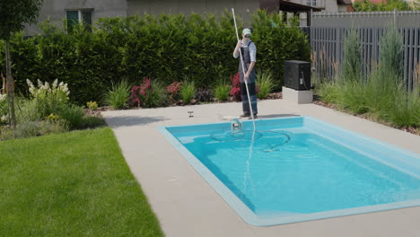 A-worker-cleans-a-swimming-pool-with-a-special-vacuum-cleaner.