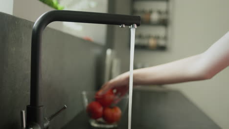 Frauenhände-Waschen-Eine-Tomate-Unter-Fließendem-Leitungswasser.