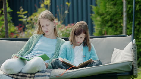 Zwei-Mädchen-Lesen-Bücher-Und-Sitzen-Auf-Einer-Gartenschaukel-Im-Hinterhof-Des-Hauses