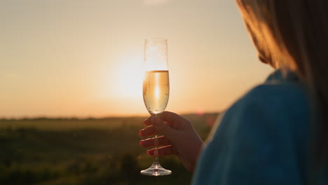 Successful-woman-with-a-glass-of-champagne-on-the-background-of-a-picturesque-valley-at-sunset