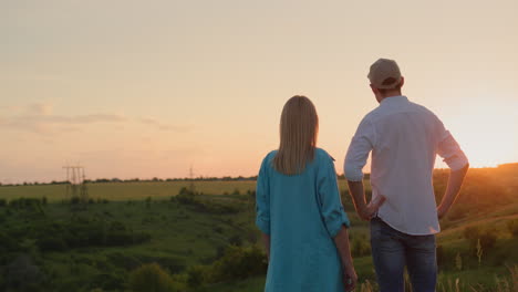 A-couple-of-farmers-look-ahead-at-a-picturesque-valley-where-the-sun-sets