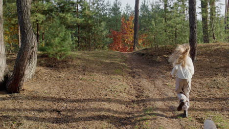 A-teenage-girl-runs-with-a-dog-along-a-path-in-a-pine-forest.