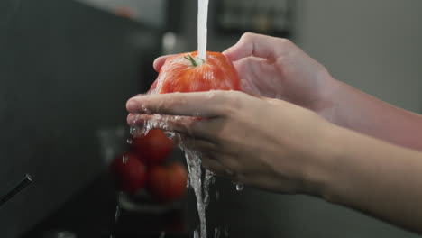 Frauenhände-Waschen-Eine-Tomate-Unter-Fließendem-Leitungswasser.-4K-Video-In-Zeitlupe