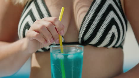 Attractive-Woman-in-bikini-shatters-ice-in-a-cocktail,-close-up-shot.