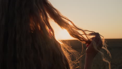 Young-woman-looks-at-her-hair-in-the-sun,-holds-a-lock-of-hair-in-her-hand