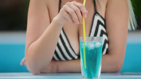Attractive-woman-drinking-a-cool-cocktail-on-the-side-of-the-pool