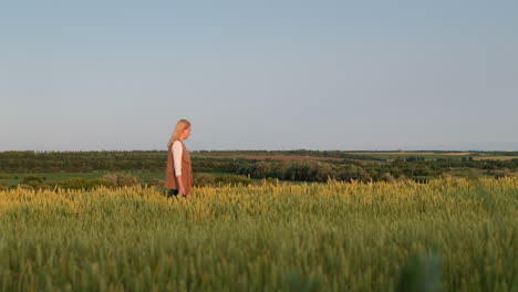 A-woman-walks-through-a-field-of-wheat-against-the-backdrop-of-a-picturesque-rural-landscape