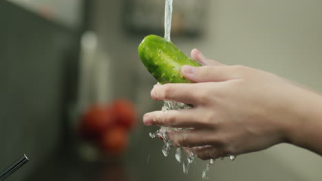 Juicy-cucumber-is-washed-under-water-from-the-kitchen-tap.-Slow-motion-4k-video
