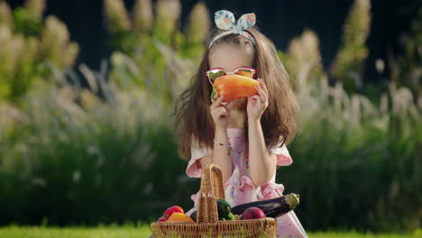 A-cute-child-is-sitting-on-the-lawn-near-a-basket-of-vegetables.-Picnic-concept