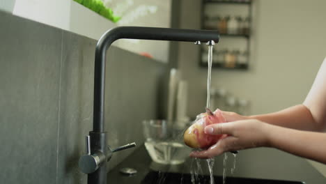 A-woman-peels-potatoes-under-running-water-from-a-kitchen-faucet.