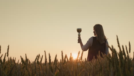 Farmer-woman-raising-champion-cup-in-wheat-field-at-sunset