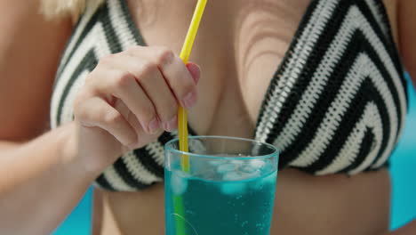 Woman-in-bikini-shatters-ice-in-a-cocktail,-close-up