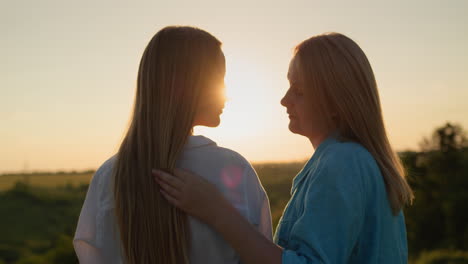 Mom-gently-communicates-with-her-teenage-daughter,-standing-in-a-picturesque-place-at-sunset.