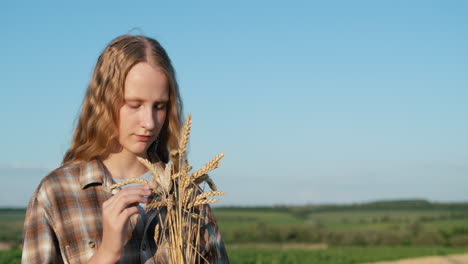 Portrait-of-a-cute-girl-with-a-bouquet-of-spikelets-on-the-background-of-a-wheat-field