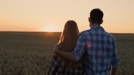 Young-couple-admiring-the-sunset-over-a-field-of-wheat