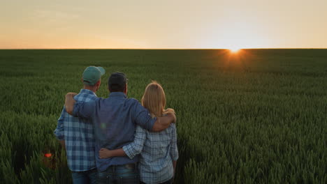 A-friendly-family-of-farmers-admiring-the-sunset-over-a-field-of-wheat
