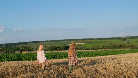 Mom-and-teenage-daughter-walking-through-a-picturesque-wheat-field