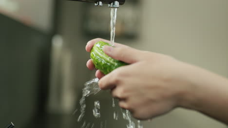 Weibliche-Hände-Waschen-Eine-Grüne-Gurke-Unter-Fließendem-Wasser-Aus-Einem-Küchenhahn