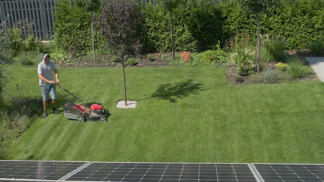 Man-mowing-the-lawn-in-the-backyard-of-the-house,-view-from-above.