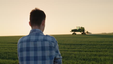 Un-Joven-Agricultor-Mira-Un-Campo-De-Trigo-Donde-Está-Trabajando-Un-Tractor