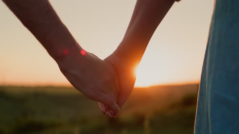 A-young-couple-holds-hands-against-the-backdrop-of-a-picturesque-valley-where-the-sun-sets
