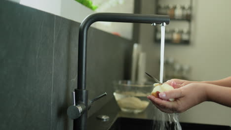 Eine-Person-Schält-Kartoffeln-Unter-Fließendem-Wasser-Aus-Einem-Küchenhahn.-4K-Video