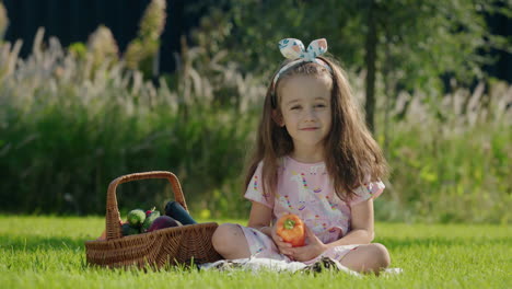 Happy-child-is-sitting-on-the-lawn-near-a-basket-of-vegetables.-Picnic-concept